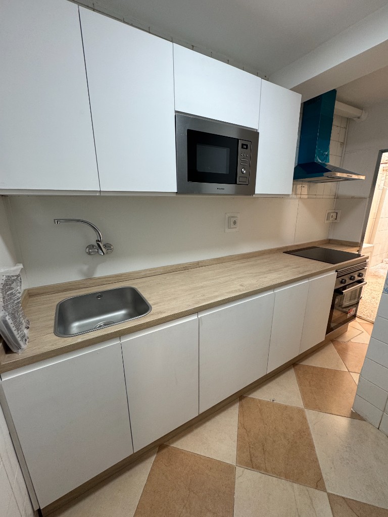 Cocina moderna con mobiliario blanco tras la reforma en Madrid