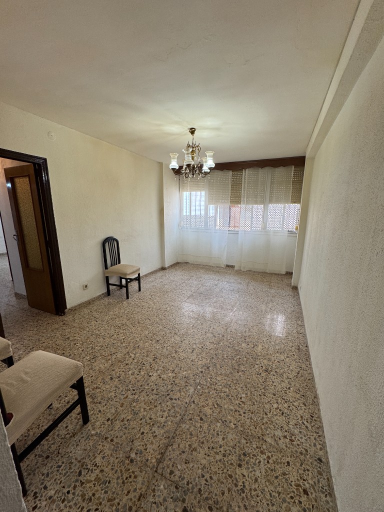 Salón anticuado con suelo de terrazo y gotelé antes de la reforma en Madrid